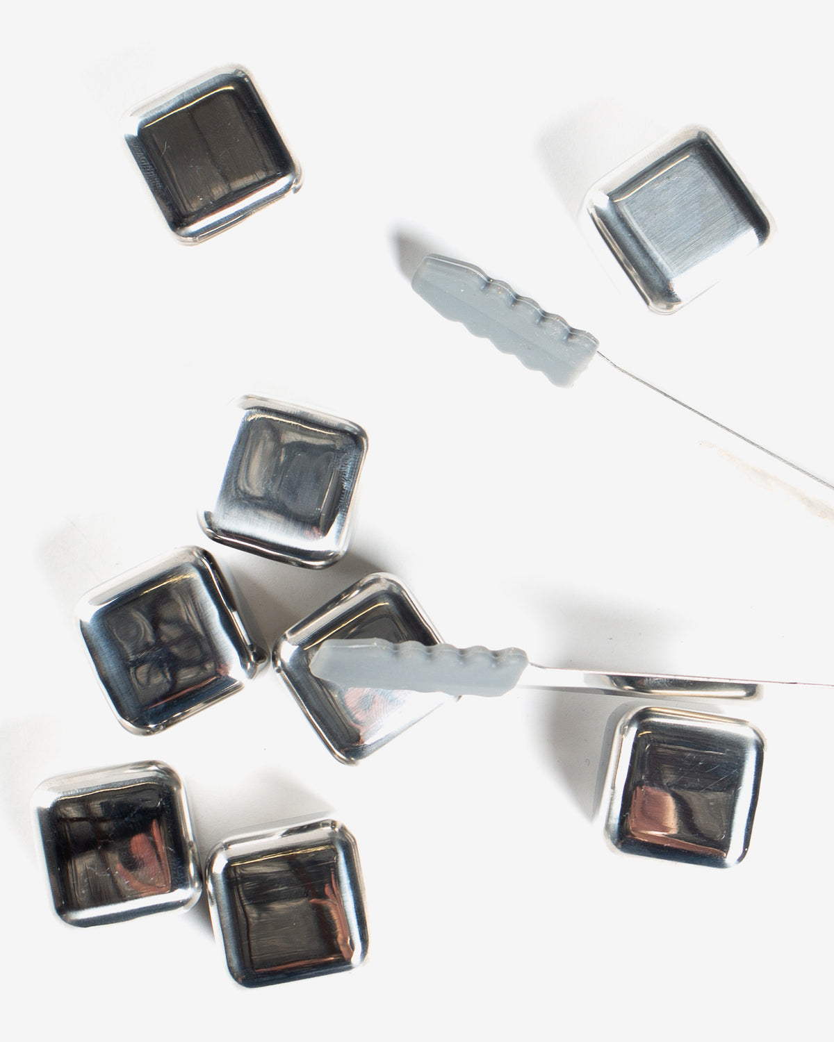 Silver square-shaped objects with reflective surfaces on a white background